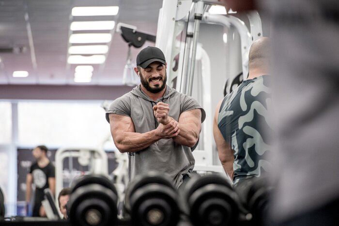 Tableau  Strong muscle bearded caucasian athlete man holding his wrist with hand during sport training injury with grimace of pain on his face indoor gym