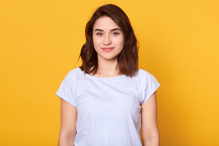 Tableau  Studio portrait of beautiful young woman with dark hair. Pretty model girl with perfect fresh clean skin looking directly at camera with charming smile, slim female having happy facial expression.