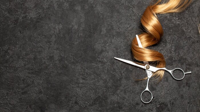 Tableau  The hairdresser. Scissors and curl of hair on a black background