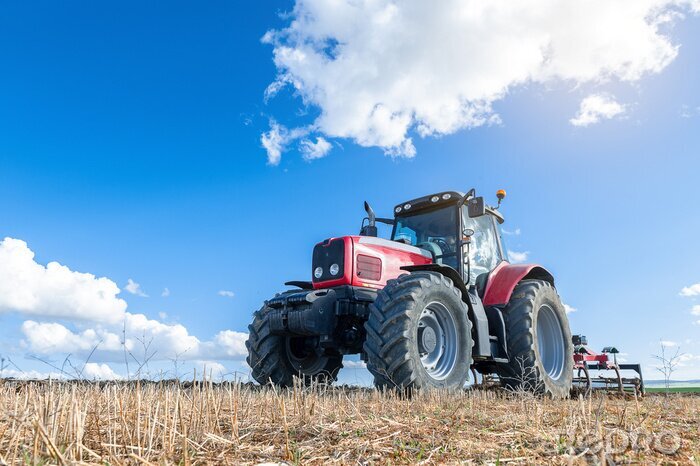 Tableau  Tracteur agricole au premier plan avec un fond de ciel bleu.