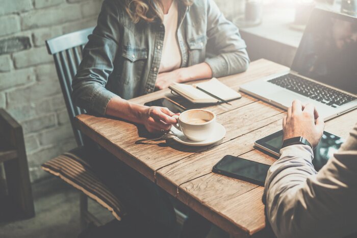 Tableau  Travail en équipe. Homme d'affaires et femme d'affaires assis à la table dans un café et discuter du plan d'affaires. Sur la table est un ordinateur portable, une tablette, un smartphone, un cahier, u