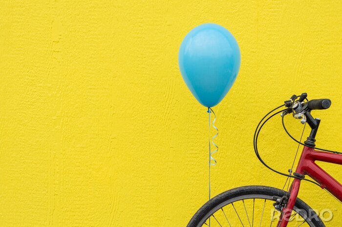 Tableau  Vélo rouge avec un ballon bleu contre un mur jaune vif.