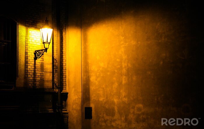 Tableau  Vieille lanterne illuminant un mur d'angle de ruelle sombre la nuit à Prague, en République tchèque. Photo presque monochromatique avec des tons jaune-brun de la lanterne comme source de lumière contr
