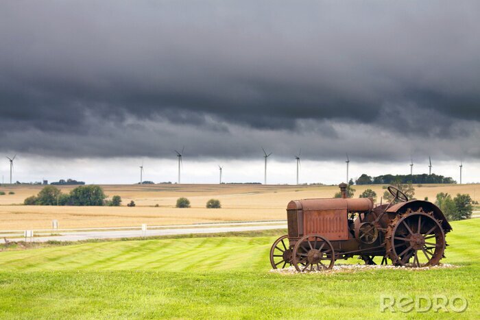 Tableau  Vieux tracteur rouillé avec un temps d'orage en arrière-plan