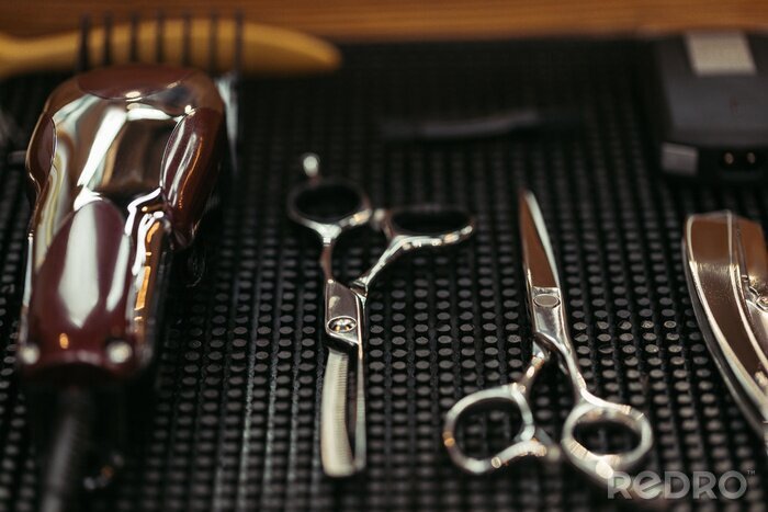 Tableau  vue rapprochée de ciseaux professionnels et tondeuse électrique dans le salon de coiffure