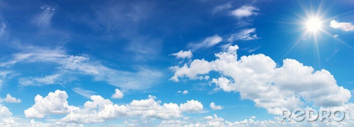 Tableau  ciel bleu avec nuages ​​et réflexion du soleil. Le soleil brille pendant la journée en été